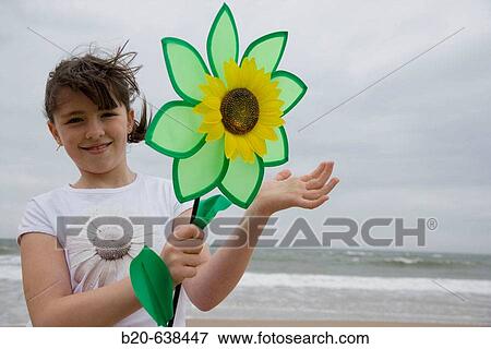 Stock Photo - Girl playing with flower-shaped weather vane. Fotosearch