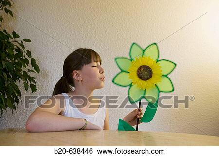 Stock Photograph - Girl playing with flower-shaped weather vane. Fotosearch