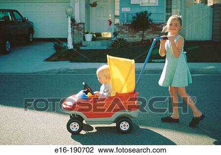 Girl pushing baby in toy car View Large Photo Image Stock Image - Girl pushing baby in toy car. Fotosearch