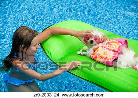 Girl puts goggles on her puppy lying on a pool raft. View Large Photo Image Picture - Girl puts goggles on her puppy lying on a pool raft.. Fotosearch