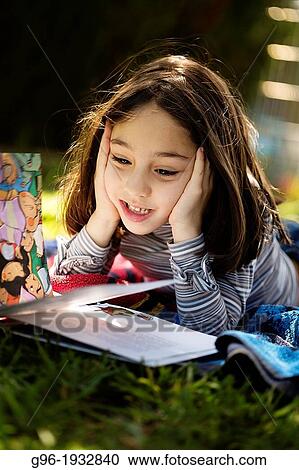 Stock Image - Girl reading a book on the grass. Fotosearch