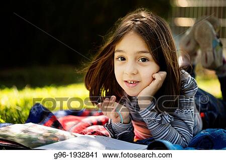 Stock Image - Girl reading a book on the grass. Fotosearch
