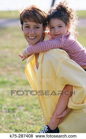 Stock Photo - girl riding piggyback on her mom. Fotosearch