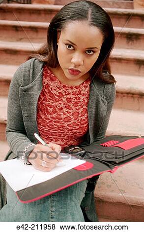 Stock Photo - Girl sitting down in the stairs writing. Fotosearch
