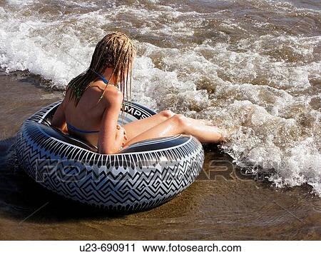 Girl sitting in a ring at the water's edge on a beach. View Large Photo Image Stock Image - Girl sitting in a ring at the water's edge on a beach.. Fotosearch