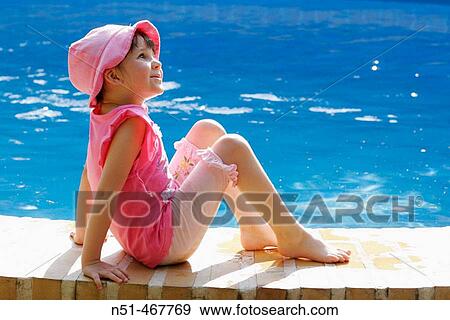 Stock Photo - Girl sitting near swimming pool. Fotosearch