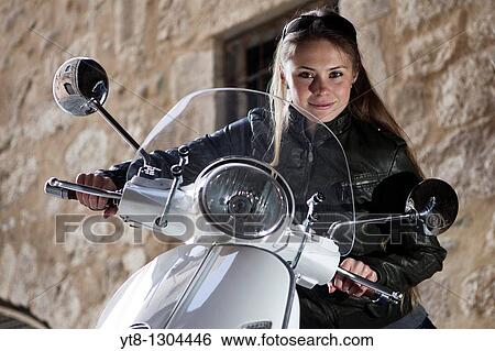 Girl sitting on a motor scooter View Large Photo Image Stock Photograph - Girl sitting on a motor scooter. Fotosearch
