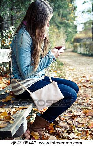 Girl sitting on a wooden bench waiting for a friend. View Large Photo Image Stock Photo - Girl sitting on a wooden bench waiting for a friend.. Fotosearch