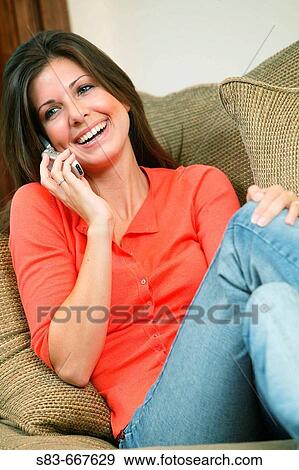 Girl sitting on couch talking on the phone View Large Photo Image Stock Photo - Girl sitting on couch talking on the phone. Fotosearch