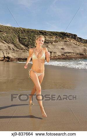 Picture - Girl sitting on the beach watching the sunset. Fotosearch