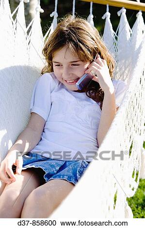 Girl speaking with her mobile phone laying on a hammock in the garden View Large Photo Image Stock Image - Girl speaking with her mobile phone laying on a hammock in the garden. Fotosearch
