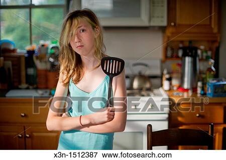 Stock Photo - Girl standing in a kitchen with a spatula. Fotosearch