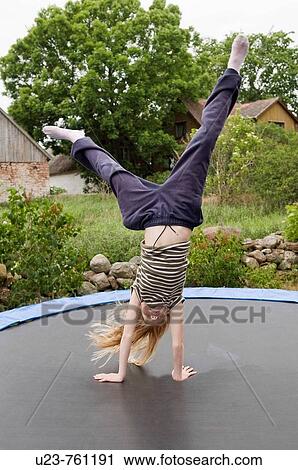 Stock Image - Girl standing on her hands on a trampolin.. Fotosearch