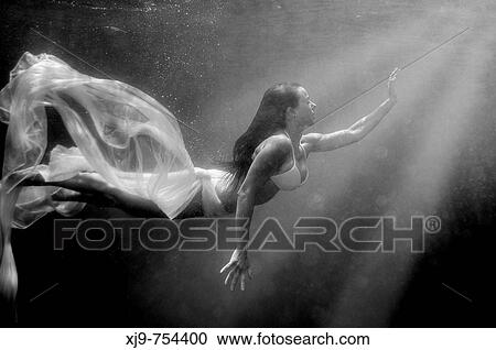 Stock Image - Girl swimming underwater, searching for the light.. Fotosearch