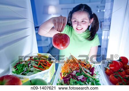Girl takes an apple from the fridge View Large Photo Image Stock Image - Girl takes an apple from the fridge. Fotosearch