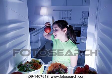 Girl takes an apple from the fridge View Large Photo Image Stock Photo - Girl takes an apple from the fridge. Fotosearch