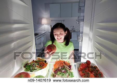 Girl takes an apple from the fridge View Large Photo Image Stock Photo - Girl takes an apple from the fridge. Fotosearch
