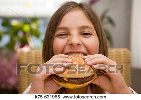 Stock Photography - Girl taking a bite out of cheeseburger. Fotosearch