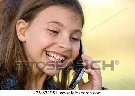 Stock Image - Girl talking on cell phone outdoors.. Fotosearch