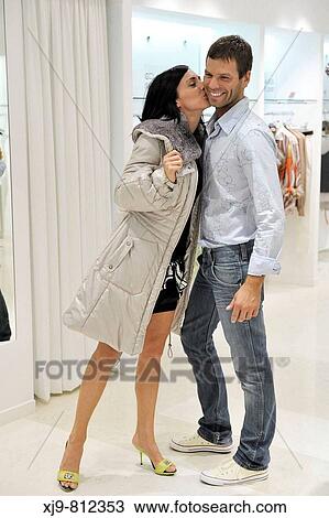 Stock Image - Girl trying coat in the shop.. Fotosearch
