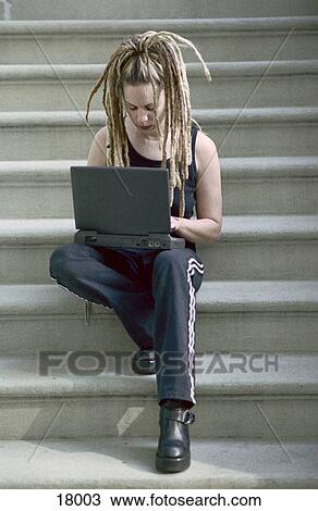 Girl typing on a laptop while sitting on steps of building View Large Photo Image Stock Image - Girl typing on a laptop while sitting on steps of building. Fotosearch