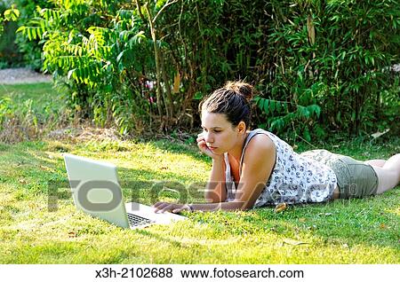 girl using a laptop computer lying on lawn in a garden, Ile de France region, France, Europe. View Large Photo Image Stock Photo - girl using a laptop computer lying on lawn in a garden, Ile de France region, France, Europe.. Fotosearch