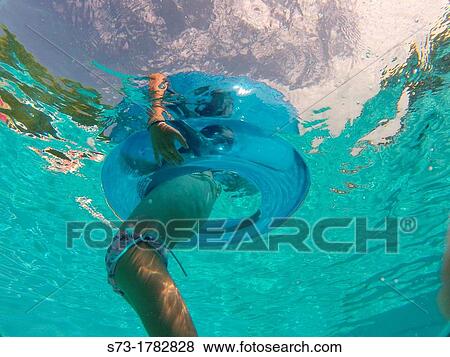 Girl using an inflatable tube in a swimming pool View Large Photo Image Stock Photo - Girl using an inflatable tube in a swimming pool. Fotosearch