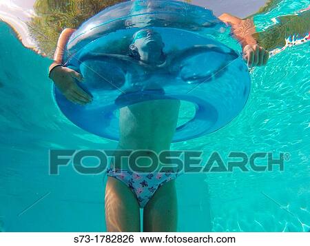 Stock Photograph - Girl using an inflatable tube in a swimming pool. Fotosearch
