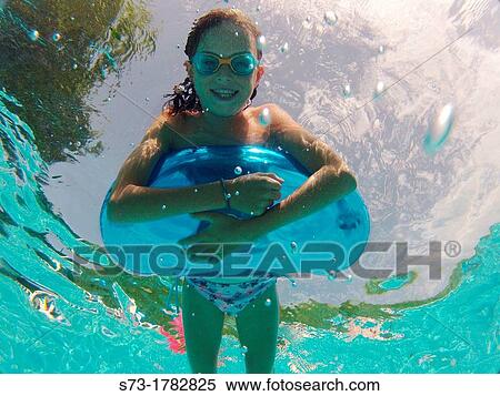 Stock Photography - Girl using an inflatable tube in a swimming pool. Fotosearch