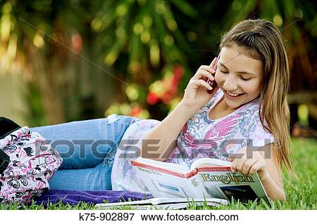 Stock Photo - girl using cell phone doing homework. Fotosearch