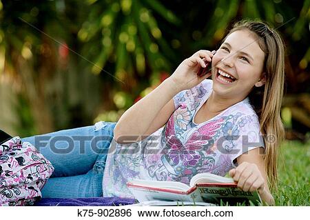 Stock Photograph - girl using cell phone doing homework. Fotosearch