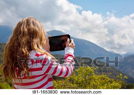Stock Image - Girl using tablet computer in the mountains. Fotosearch