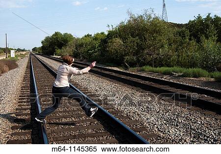 Girl walking on train tracks View Large Photo Image Stock Photography - Girl walking on train tracks. Fotosearch