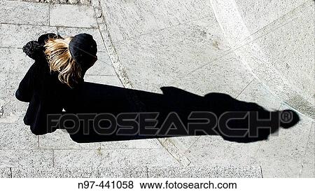 Girl watching something in her hands with a strong shadow on a stone floor View Large Photo Image Stock Photo - Girl watching something in her hands with a strong shadow on a stone floor. Fotosearch