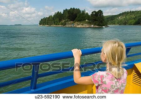 Stock Image - Girl watching the islands from a small car ferry. Sweden.. Fotosearch