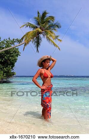 Stock Image - Girl watching the Ocean at the seashore, Biyadhoo island, Maldives. Fotosearch