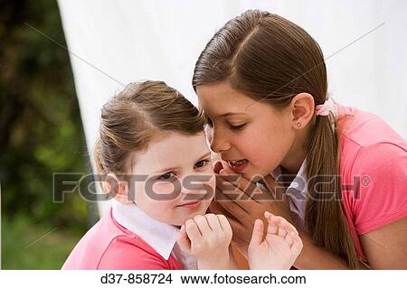Girl whispering a secret to her sister View Large Photo Image Picture - Girl whispering a secret to her sister. Fotosearch