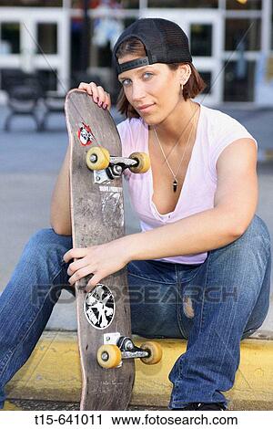 Girl with a skateboard sitting on the sidewalk. View Large Photo Image Stock Image - Girl with a skateboard sitting on the sidewalk.. Fotosearch