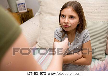 Stock Image - Girl with arms folded getting a scolding. Fotosearch