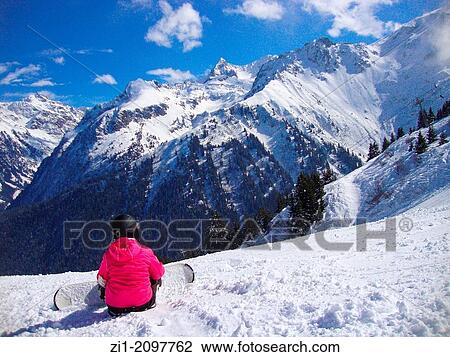 girl with snowboards sit in the snow and enjoys view at the Alps in Prapoutel, France View Large Photo Image Stock Image - girl with snowboards sit in the snow and enjoys view at the Alps in Prapoutel, France. Fotosearch