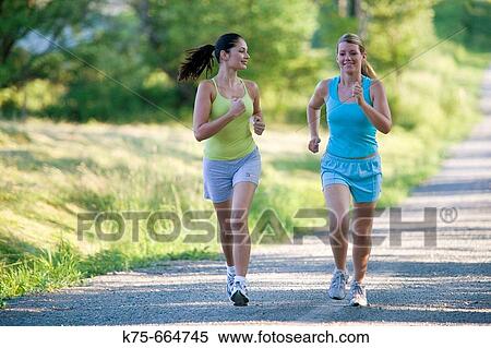 Girlfriends jogging together on country road View Large Photo Image Stock Photography - Girlfriends jogging together on country road. Fotosearch