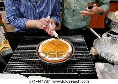 Girlfriends making cake: piping icing on cake View Large Photo Image Stock Photo - Girlfriends making cake: piping icing on cake. Fotosearch