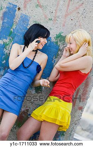 Stock Image - Girlfriends talk to each other using cellphones. Fotosearch