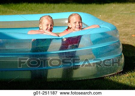 Girls ages play in an inflatable kiddie pool in front yard View Large Photo Image Stock Photo - Girls ages play in an inflatable kiddie pool in front yard. Fotosearch