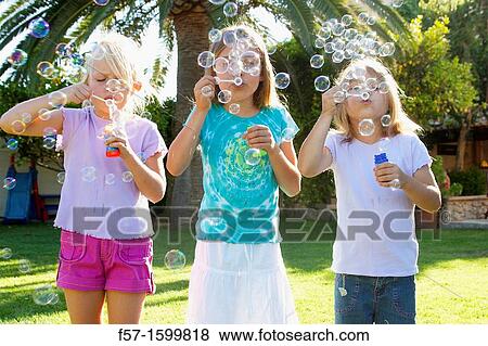 Girls blowing bubbles View Large Photo Image Stock Photo - Girls blowing bubbles. Fotosearch