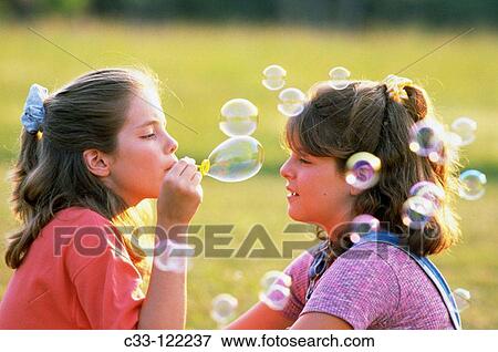 Girls blowing soap bubbles View Large Photo Image Stock Photo - Girls blowing soap bubbles. Fotosearch