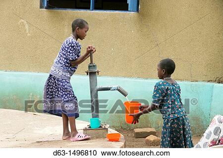 Stock Image - Girls collecting water from hand pump, Home of Compassion for the sick and needy, Kigera village, near Musoma, Tanzania. Fotosearch