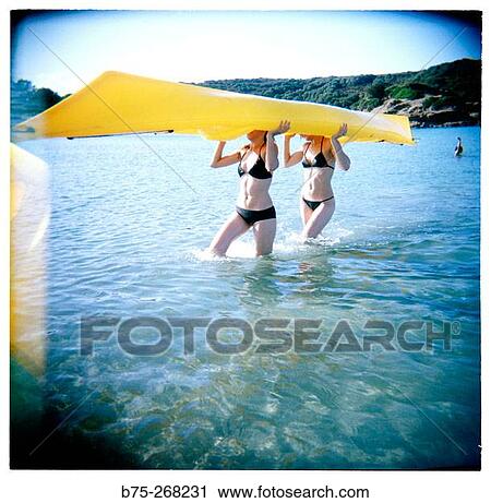 Girls holding a yellow canoe at the beach View Large Photo Image Stock Image - Girls holding a yellow canoe at the beach. Fotosearch