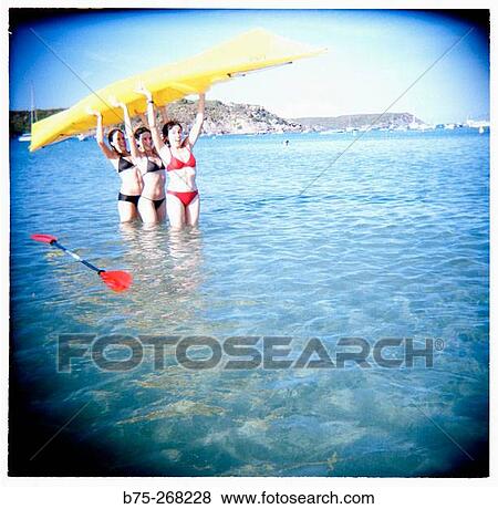 Girls holding a yelow canoe on the beach View Large Photo Image Stock Photo - Girls holding a yelow canoe on the beach. Fotosearch