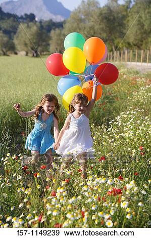Girls in meadow with balloons View Large Photo Image Stock Photo - Girls in meadow with balloons. Fotosearch